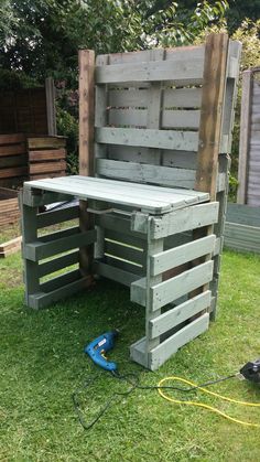 an outdoor bench made out of wooden pallets in the grass next to a fence