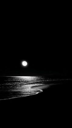 a full moon is seen over the ocean on a black and white night time photo