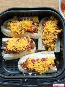 four hot dogs with toppings in a container