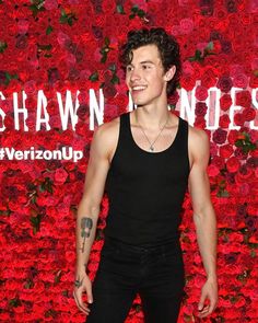 a young man standing in front of a red flower wall with the words swann jones on it