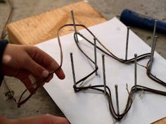 a person is working on some kind of wire art project that looks like an upside down tree