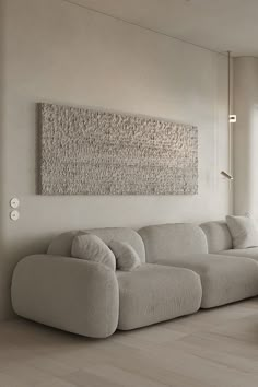 a living room with a large white couch in front of a painting on the wall