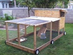 a small chicken coop in the grass with an open roof and door on wheels that is attached to it's sides