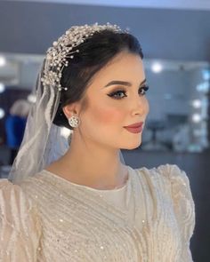 a woman in a wedding dress with a veil and tiara on her head, looking off to the side