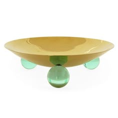 a yellow bowl with two green glass balls in the bottom and an upside down design