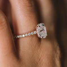 a woman's hand with a diamond ring on top of her finger and an engagement band