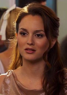 a close up of a woman with long hair wearing a gold dress and looking at the camera