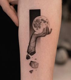 a woman's arm with a piece of artwork on it and the moon in her hand