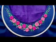 a close up of a pink flowered necklace on a purple cloth with white beading