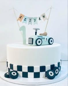 a birthday cake decorated with a race car and bunting banner for the number one