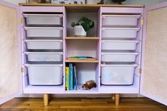 a purple cabinet with plastic bins and books on it's shelves in front of a wooden floor