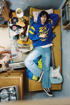 a young man laying on top of a bed next to a table with a guitar