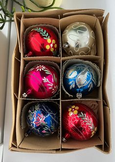 an open cardboard box filled with different colored ornaments