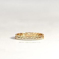 a yellow gold wedding band with small diamonds on the inside and outside, set against a plain white background