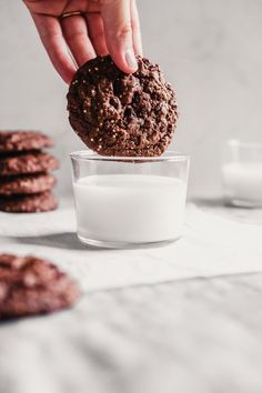 a person is dipping chocolate cookies into a glass of milk