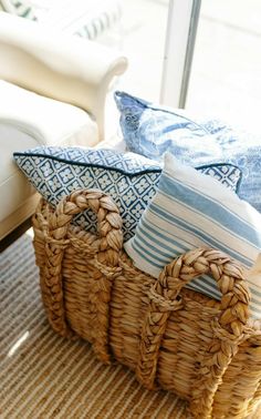 a wicker basket filled with blue and white pillows