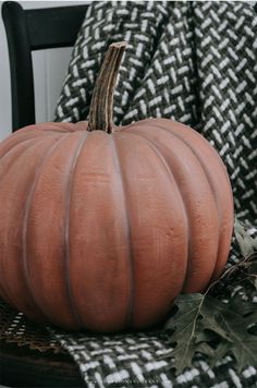 a large pumpkin sitting on top of a chair next to a black and white blanket