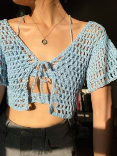 a woman wearing a blue crochet top with an open back and short sleeves