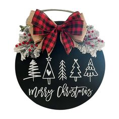 a merry christmas sign hanging on the side of a wall with pine trees and evergreens