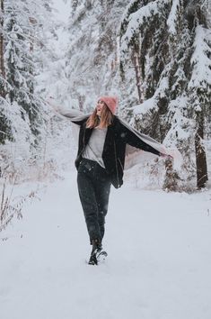 a woman walking through the snow with her arms outstretched