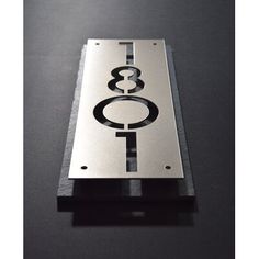 a metal plaque with the number eight on it's front and back sides, sitting on a black surface