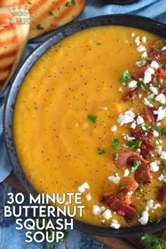 a bowl of butternut squash soup with bacon and feta cheese on the side