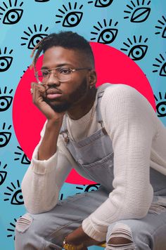 a man with glasses sitting on top of a stool next to an eye wallpaper