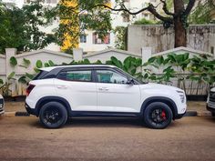 a white suv parked in front of some trees