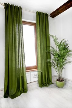 a green curtain in front of a window with a potted plant next to it