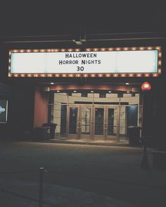 an empty theater entrance at night with lights on the marquee that says halloween horror nights 30