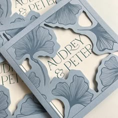 three wedding cards with the names and date printed on them, one in blue paper