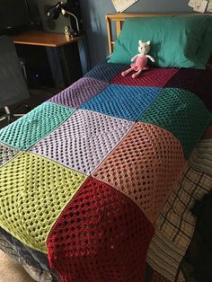 a multicolored crocheted blanket on top of a bed in a bedroom