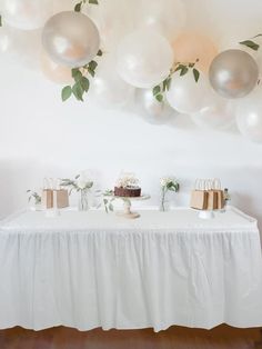 a white table topped with cake and balloons