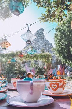 the tea cups and saucers are sitting on the table in front of the amusement park ride