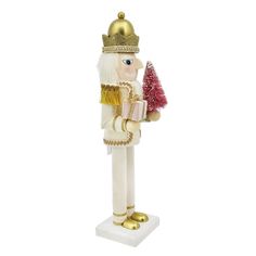 a nutcracker holding a christmas tree ornament on a white base with gold trim