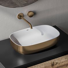 a modern bathroom sink with gold faucet and black countertop in front of a circular mirror