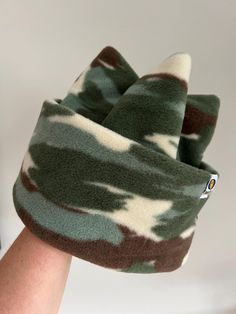 a person wearing a green and white camo beanie with a cell phone in their hand