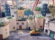 many pots with plants in them are on the table and there is a toy truck next to them