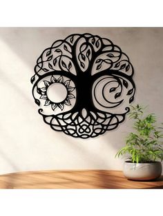 a metal tree wall hanging on the side of a white wall next to a potted plant