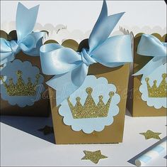 three small boxes with blue and gold crowns on them, one has a light blue bow