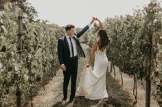 a newly married couple walking through the vineyard