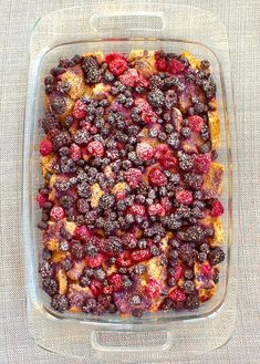 a casserole dish filled with berries on top of a cloth covered tablecloth