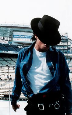 a man wearing a cowboy hat standing in front of a stadium