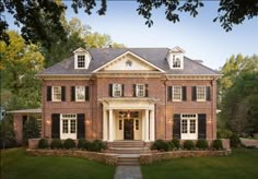 a large brick house with white trim and black shutters