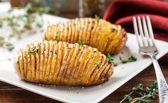 two potato wedges on a white plate next to a fork