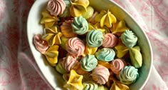 a bowl filled with colorfully decorated cookies on top of a pink and white table cloth