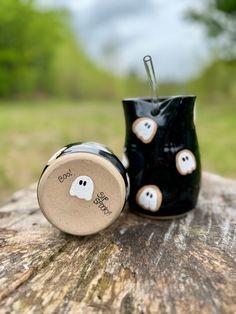 a black cup sitting on top of a wooden table next to a small white ghost