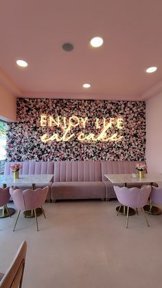 the interior of a restaurant with pink chairs and floral wallpaper on the back wall