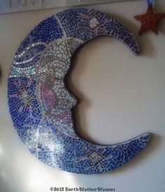 there is a mosaic moon on the wall next to two small stars and a candle holder