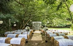 an outdoor wedding setup with hay bales and white linens on the aisle, surrounded by greenery